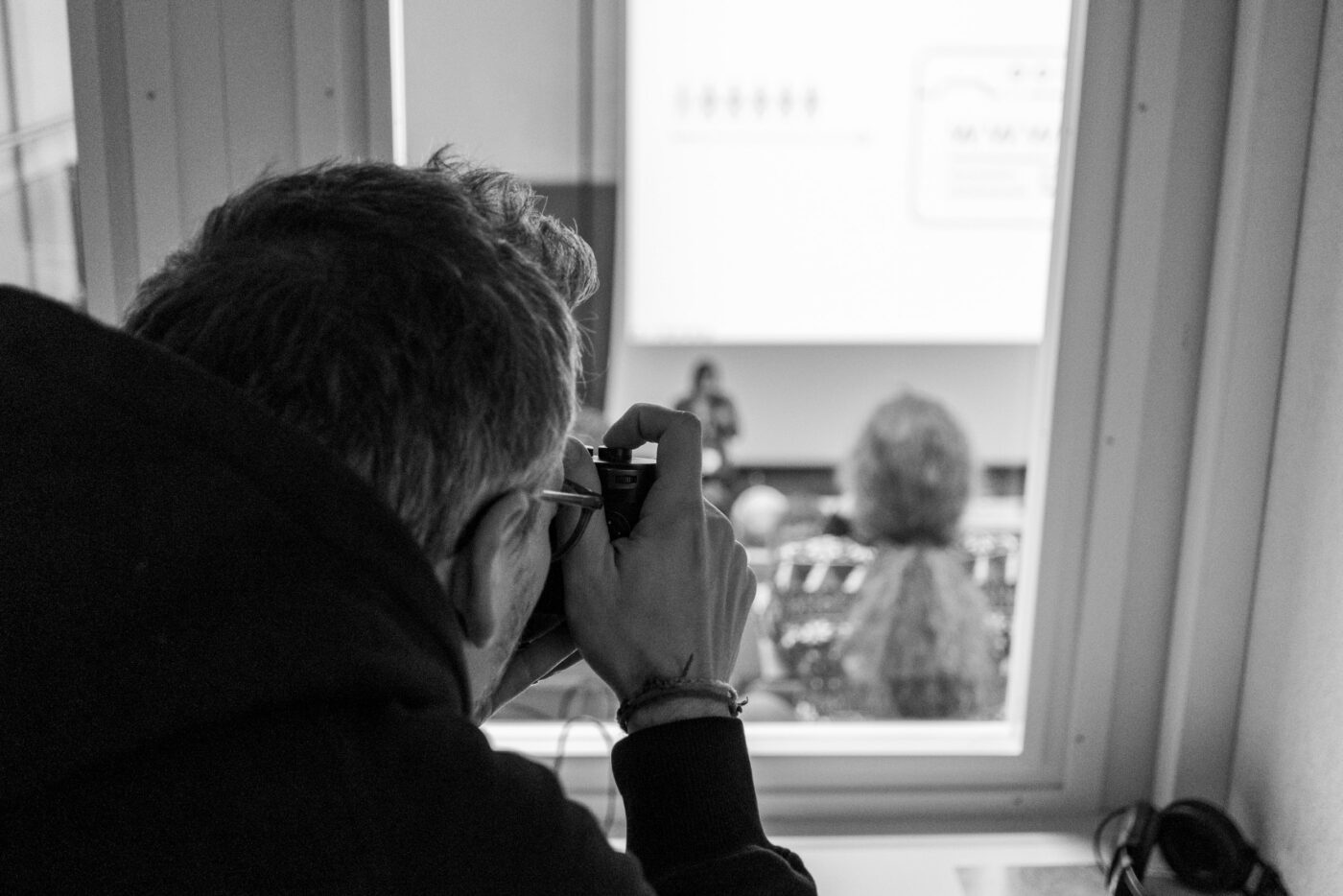 Florian fotografiert einen Talk aus dem Audio-Booth des "Aula"-Saals.